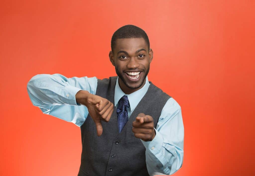 Closeup portrait of sarcastic young man showing one thumbs down sign hand gesture