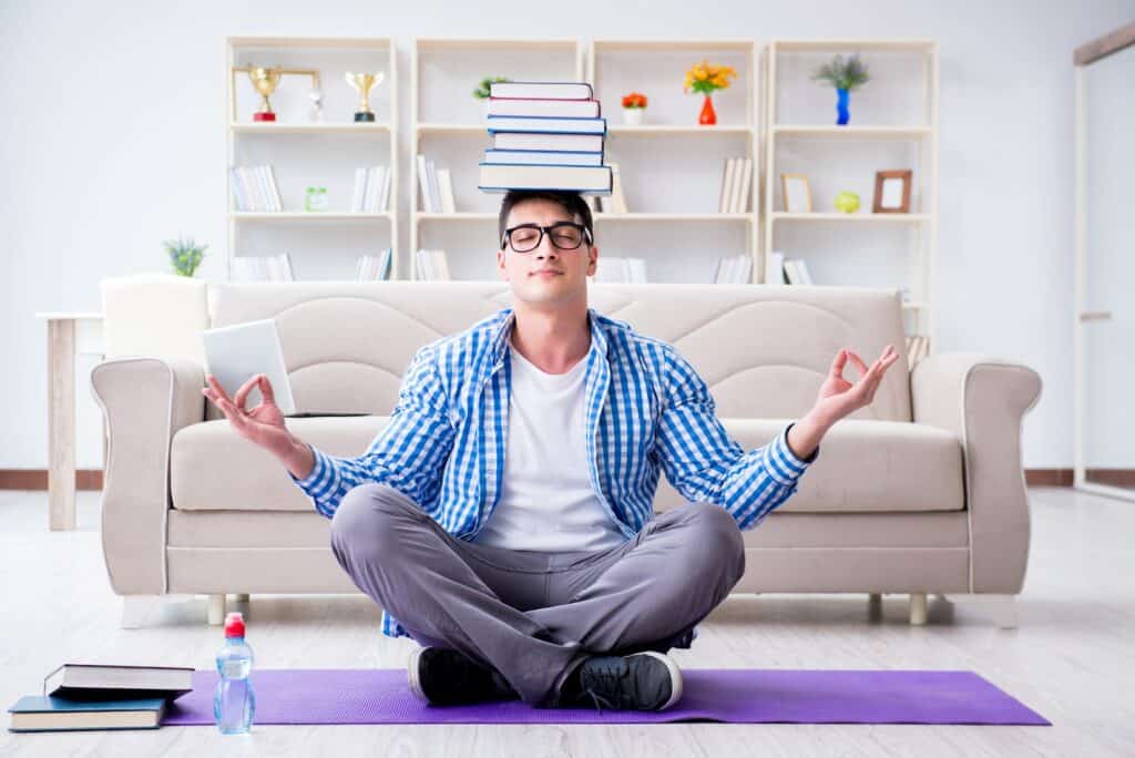 man-meditating-while-balancing-stack-of-books-on-head