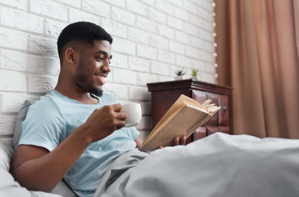 man-enjoying-book-in-bed-with-coffee