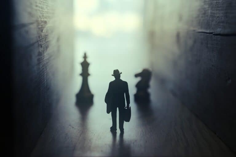 silhouette-of-man-in-dark-alley-with-chess-pieces