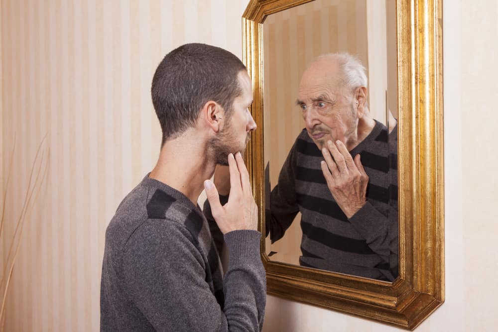 man-looking-at-older-self-in-mirror