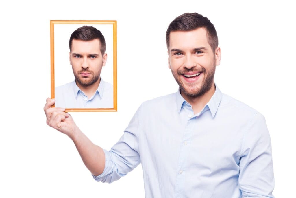 man-in-shirt-holding-a-picture-of-himself-with-upset-face-and-smiling-while-standing-against-white-background