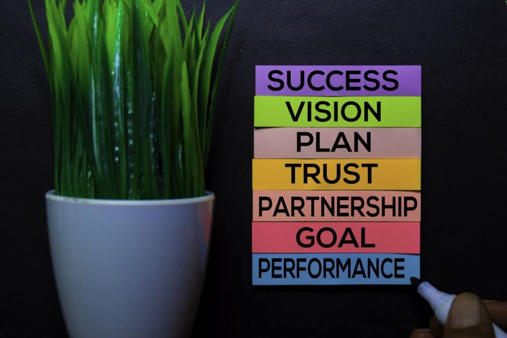 success-vision-plan-trust-partnership-goal-performance-text-on-sticky-notes-isolated-on-black-desk-mechanism-strategy-concept