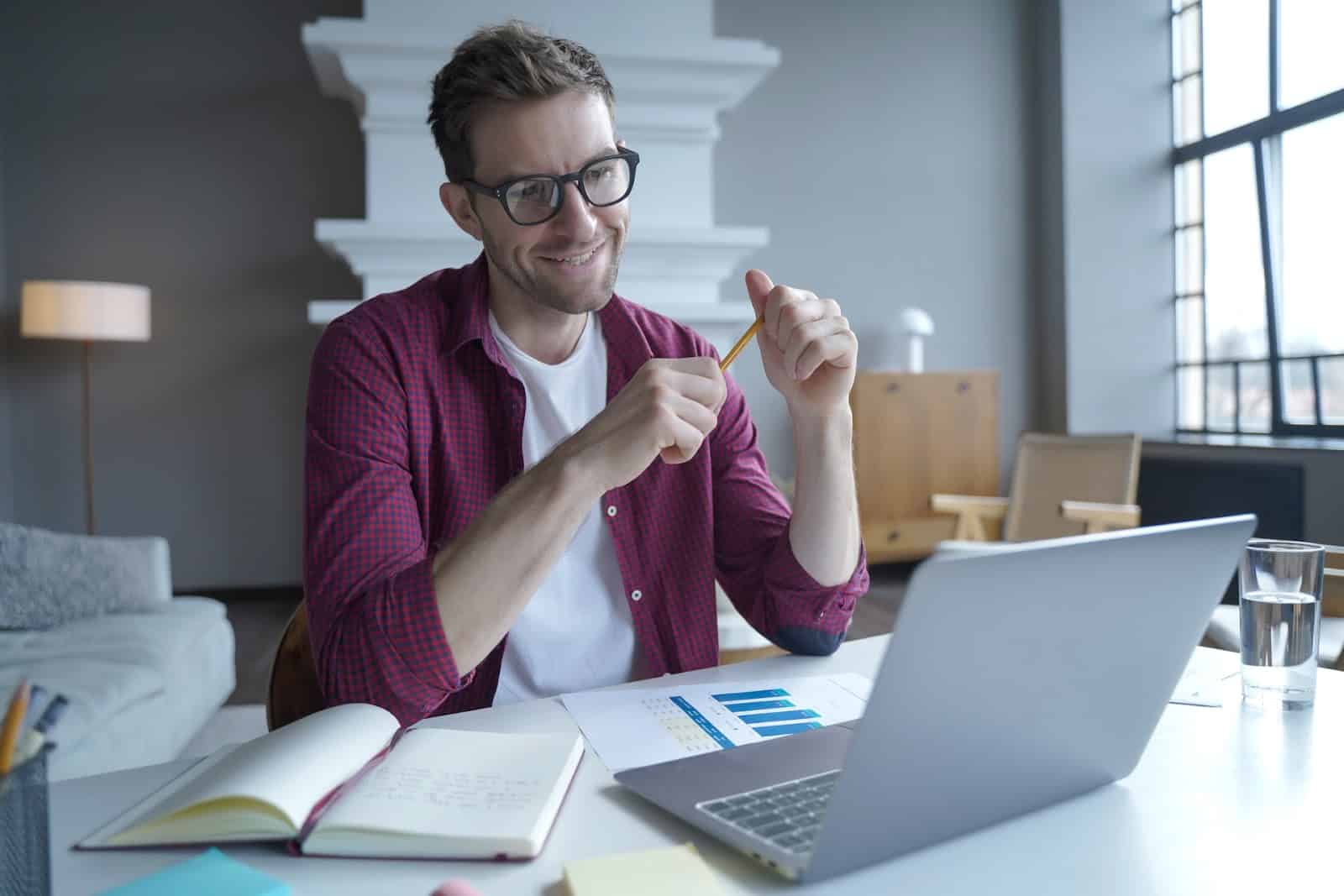 young-male-entrepreneur-in-glasses-having-pleasant-online-conversation-with-colleagues