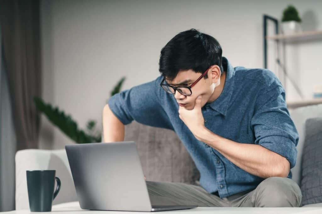 pensive-thoughtful-serious-asian-man-in-eyeglasses-looking-at-laptop-screen-thinking-for-solution-to-solve-the-problem