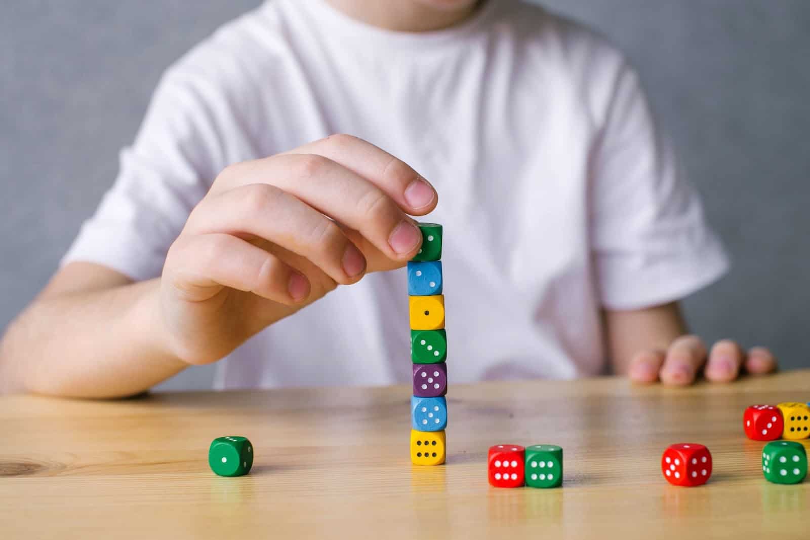 boy-plays-with-colorful-dice-cubes-builds-a-tower-up